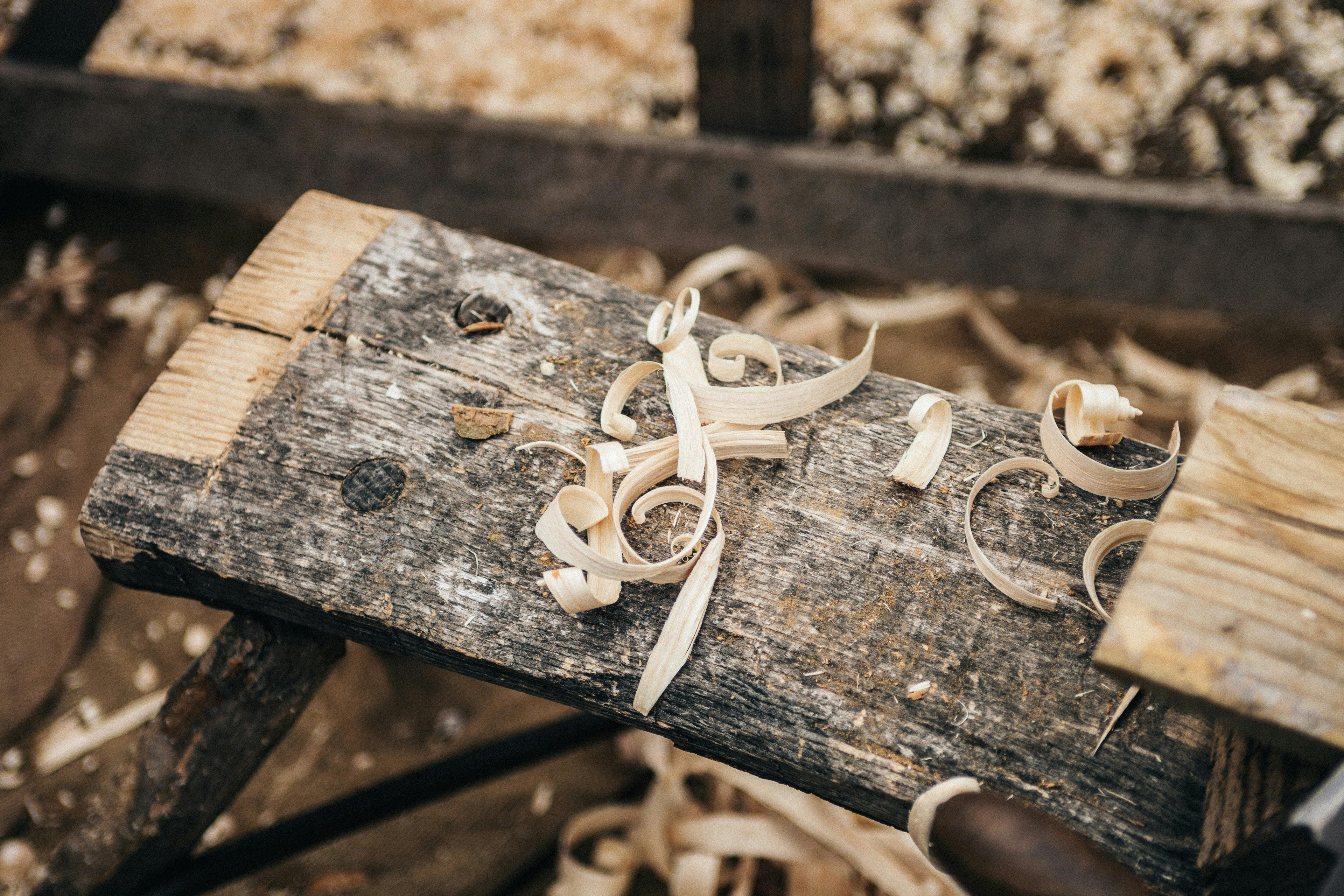 Wooden surface with wood shavings and a small object on a blurred background